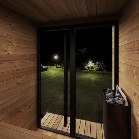 Wooden sauna interior with a view of a garden at night