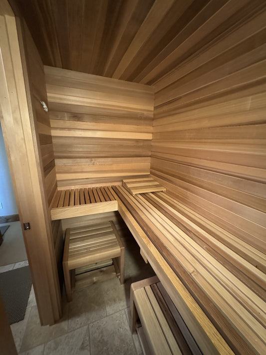 Finished closet sauna with an L-shaped cedar upper bench and movable lower benches