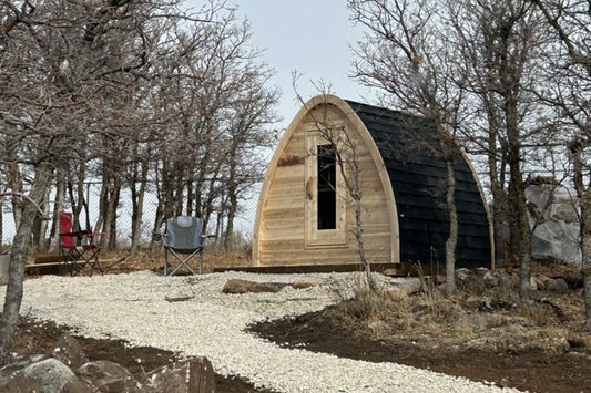 Cedar pod sauna at the end of a gravel path in a wooded backyard