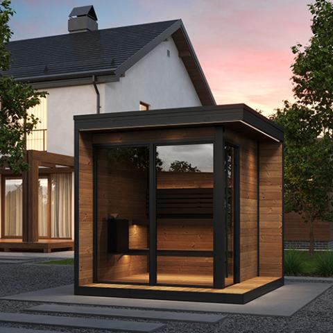 Modern outdoor sauna with wooden exterior and glass doors, set against a house and trees.