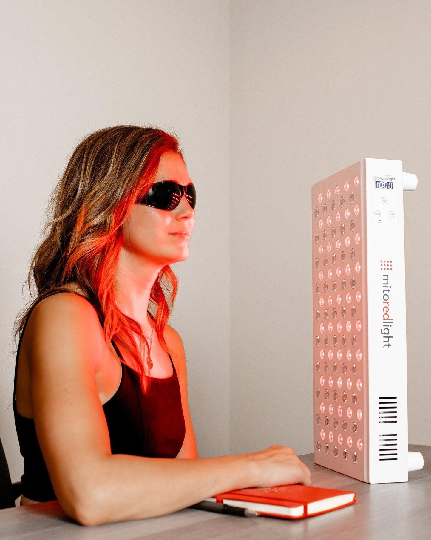 Woman using MitoMid Red Light Therapy Panel